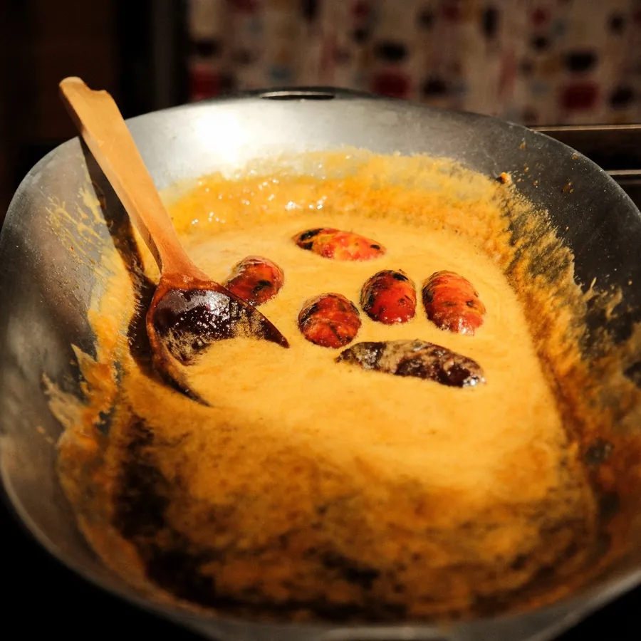 Palm fruit in a pan of bright orange palm oil.
