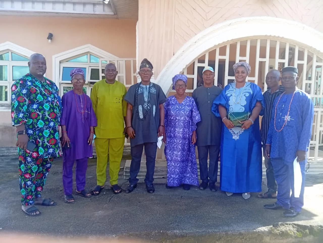 The Kabiyesi of Ofosu and his chiefs standing with the President outside a house.